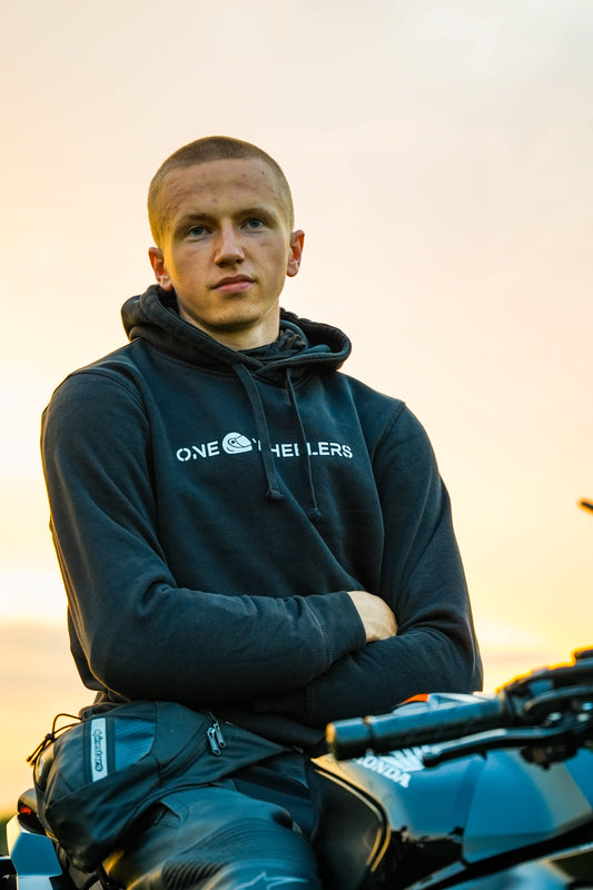 Rider wearing the black Onewheelers Crew Hoodie while sitting on a Honda sport bike at sunset, showcasing premium Onewheelers motorcycle streetwear for bikers.